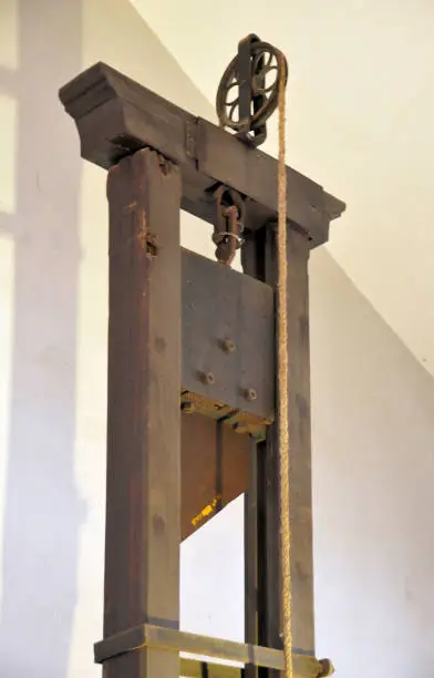 Guillotine - tall, upright frame with a weighted and angled blade suspended at the top.