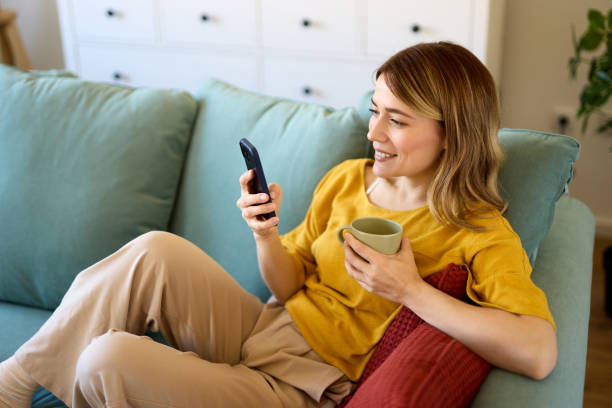 istock Woman using smartphone while drinking coffee at her home in the morning 1475316939