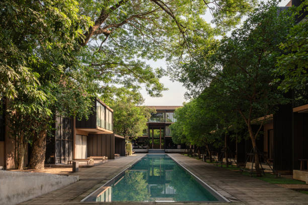 Kanchanaburi, Thailand - May 05 2021 : Beautiful modern tropical resort with tree covered reflection on swimming pool