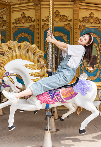 The beautiful girl riding the merry-go-round at the amusement park