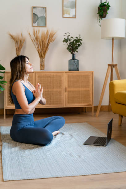 istock Young woman meditating in living room 1475320856