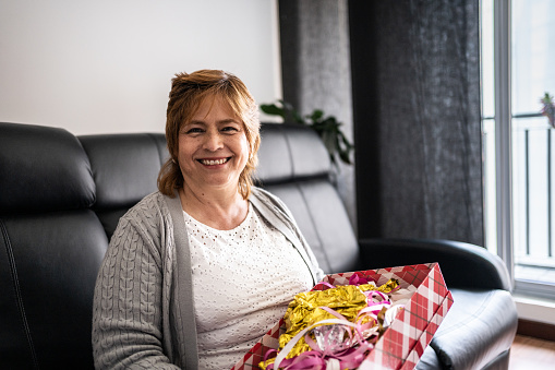 Portrait of a mature woman holding the her present in the living room at home