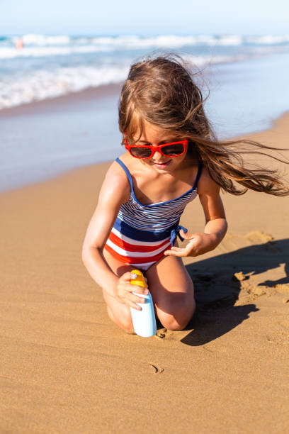 istock Little Girl applying sunscreen on the beach 1475322585
