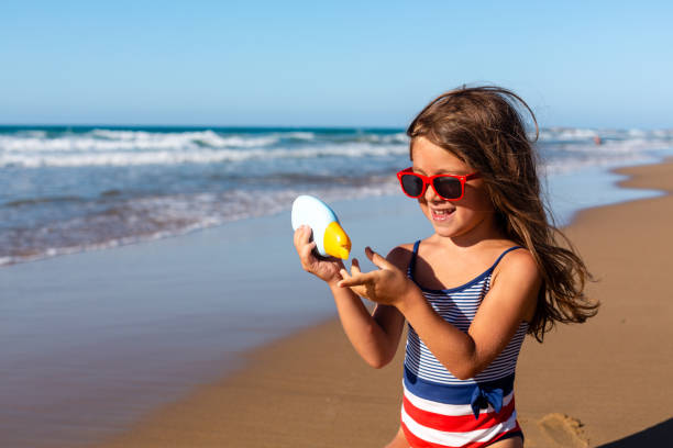 istock Little Girl applying sunscreen on the beach 1475323176