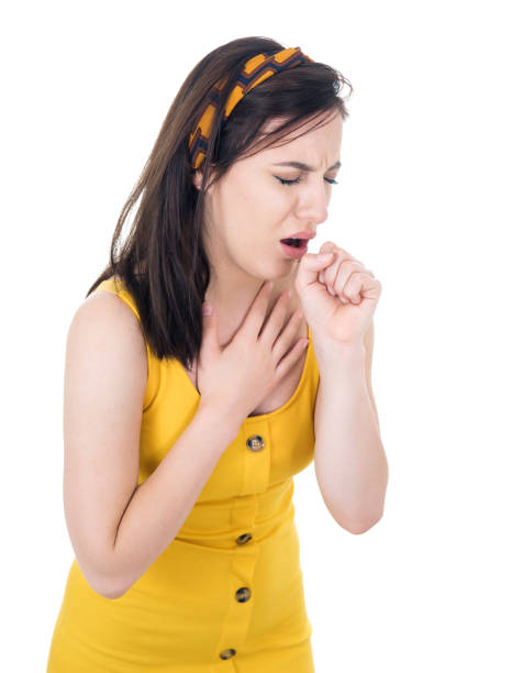 Young woman feeling ill with a sore throat and flu symptoms, coughing with mouth covered, isolated on white background stock photo