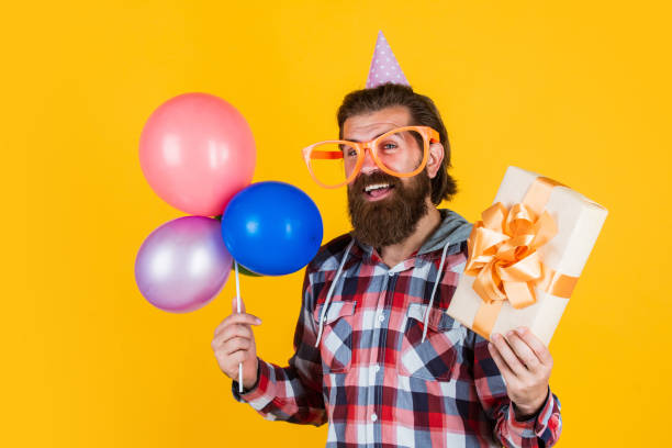 istock Buying and selling. Party Elements and holiday objects. Multi colored fun. best party for retirement. cheerful man with beard hold present. hipster smiling with balloon. Celebrating happy party 1475323660