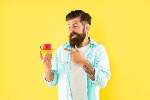 hipster with beard point finger on coffee cup on yellow background, coffee cup.