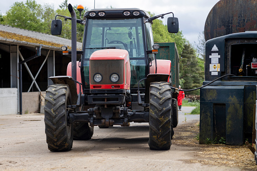 A shot of a red agricultural tractor parked on the courtyard of a sustainable farm in Northumberland in northeast England. The tractor is been refuelled.