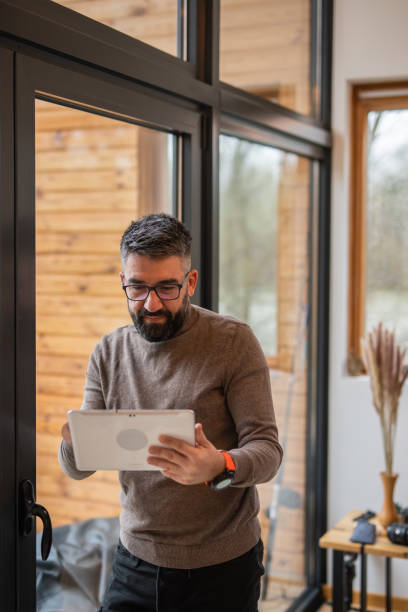 istock One man caucasian working at home on tablet behind the window, home office using technology concept 1475328779