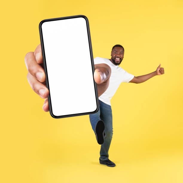 istock Cheerful Black Man Showing Cellphone Screen Over Yellow Background, Square 1475329048