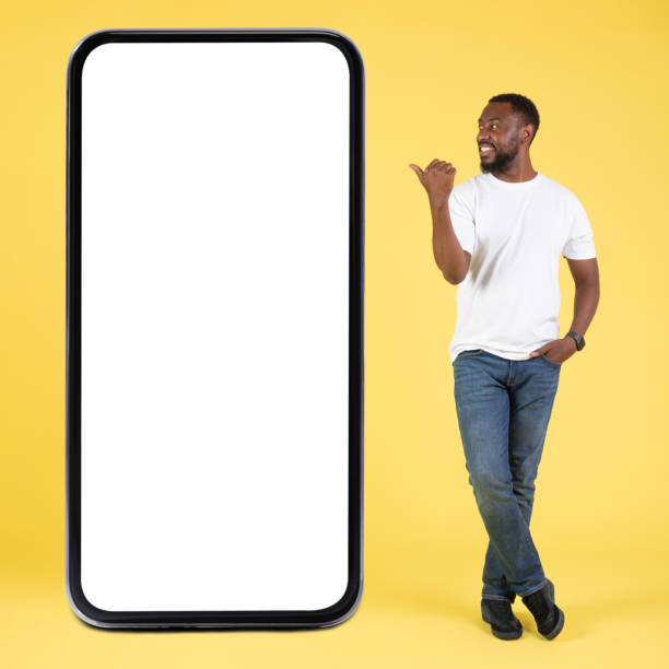 istock African Man Near Big Cellphone Pointing At Screen, Yellow Background 1475329059