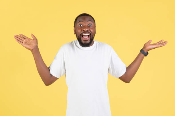 istock Cheerful African American Guy Shrugging Shoulders Over Yellow Studio Background 1475329066