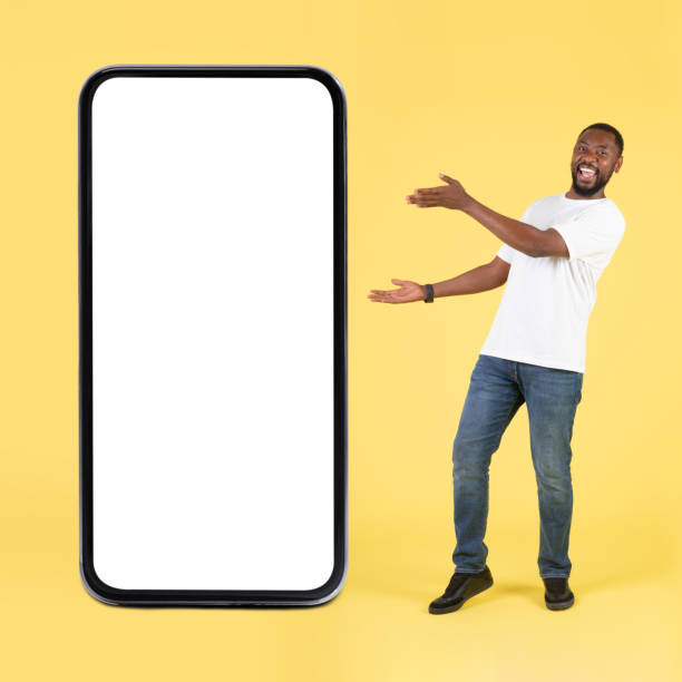 istock Joyful Black Guy Showing Large Phone Screen Over Yellow Background 1475329079