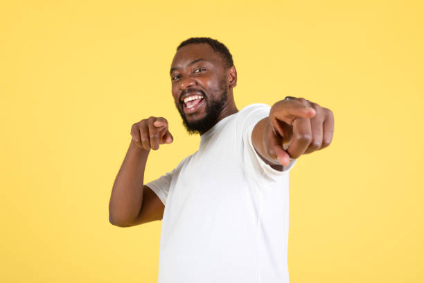 istock Black Guy Pointing Fingers Looking At Camera Over Yellow Background 1475329376