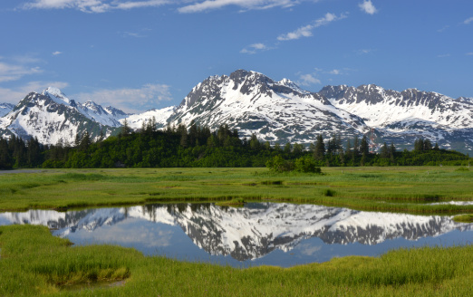 View of the Chugach Mountains still covered with a snow, reflecting in a tidal pool. Picture taken on an exceptionally beautiful June afternoon from the Edgerton Highway in Valdez, Alaska, USA.