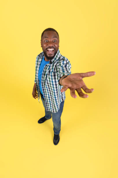 istock Black Guy Showing Invisible Object Shouting Stretching Hand, Yellow Background 1475330248