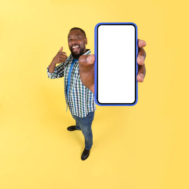istock African American Man Showing Big Smartphone Blank Screen, Yellow Background 1475330276