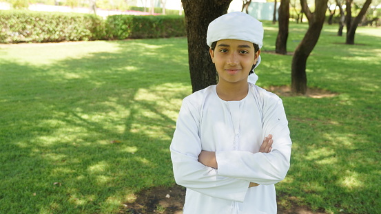 Young Arab Middle Eastern boy wearing Ghutra dishdash Thumbs Up and looking front at the camera.
