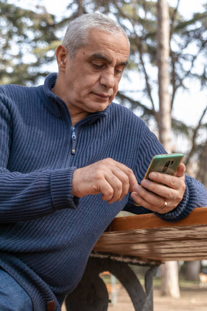 istock Senior man sitting on the bench and using smartphone 1475336858