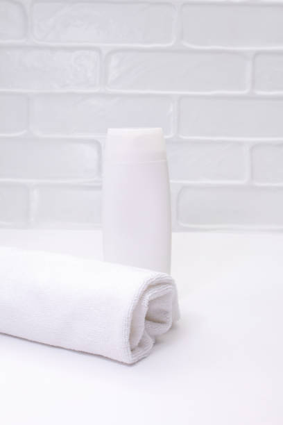 istock White bottle mockup with towel on table in bathroom. Cleanliness, care. Vertical. Copy space 1475339550