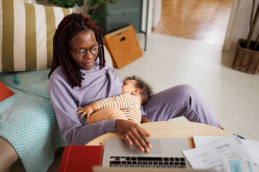 Woman working from home while breastfeeding her baby boy