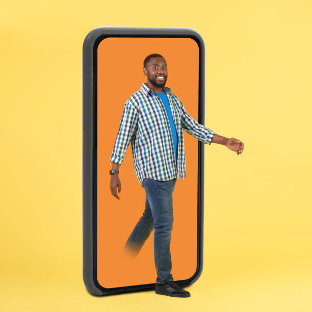 istock Black Guy Stepping Out Of Huge Smartphone Screen, Yellow Background 1475341888