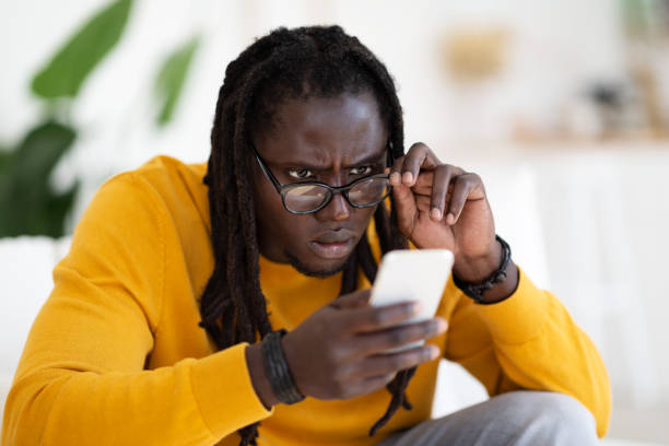 istock Eyesight Problems Concept. Young Black Man Wearing Eyeglasses Reading Message On Smartphone 1475341985