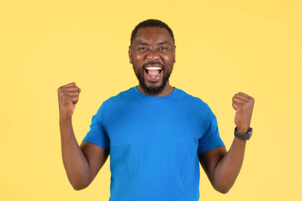 istock Joyful Black Guy Shaking Fists In Joy On Yellow Background 1475342134