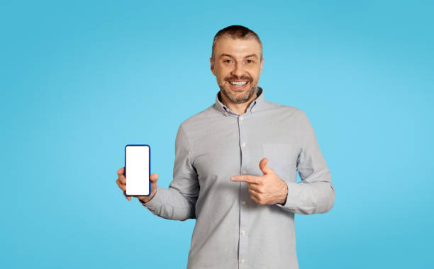 istock Middle Aged Male Showing Cellphone Blank Screen On Blue Background 1475342308