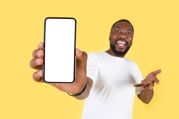 istock Cheerful Black Man Showing Huge Smartphone Empty Screen, Yellow Background 1475342378