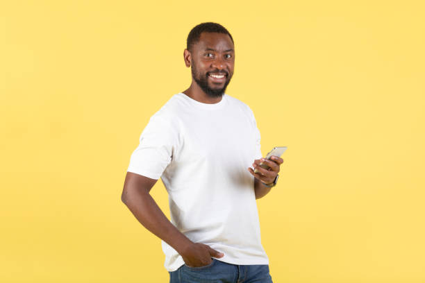 istock Happy African Man Using Mobile Phone Texting Over Yellow Background 1475342390