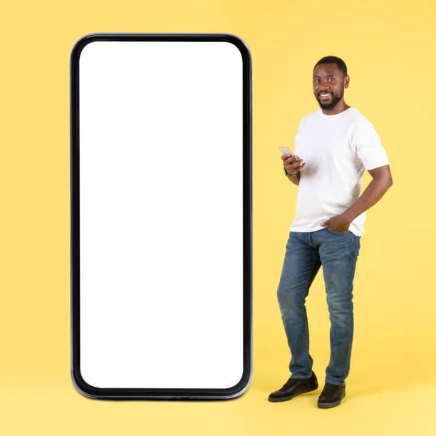istock African Male Using Phone Standing Near Huge Smartphone In Studio 1475342396