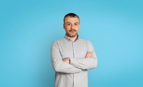istock Serious Middle Aged Businessman Crossing Hands Posing Over Blue Background 1475342486