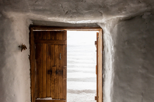 Wooden door in snow building leading to snow steps