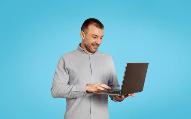 istock Happy Middle Aged Male Using Laptop Computer Over Blue Background 1475343214