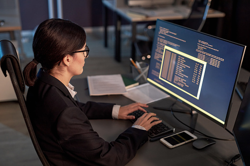Female Software Developer Writing Code While Using Computer At ...