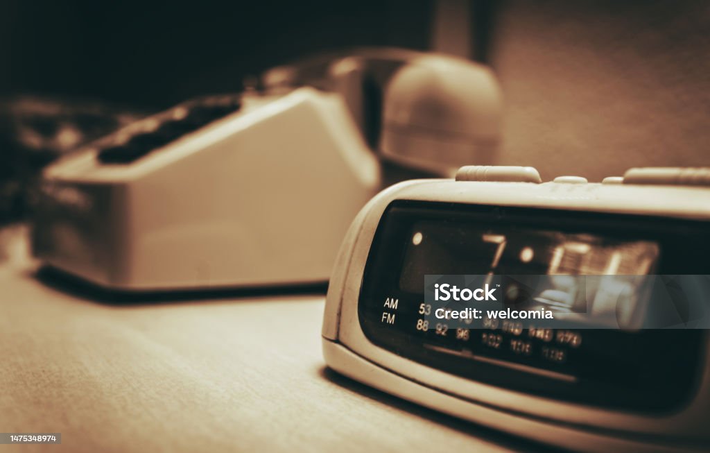 Vintage Hotel Room alarm Clock and the Analog Phone Vintage Hotel Room alarm Clock and the Analog Phone Close Up. Sepia Color Grading. Alarm Clock Stock Photo