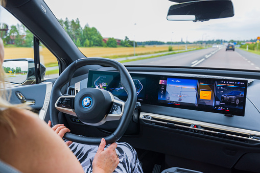 Sweden. Uppsala. 08.18.2022. Close up interior view of BMW iX 40 on  road. Woman driver in vehicle drives on highway.