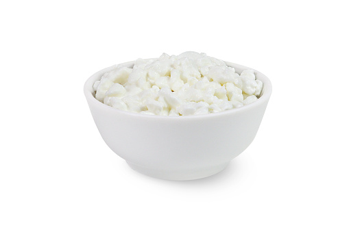 Cottage cheese in a white bowl on an isolated white background.