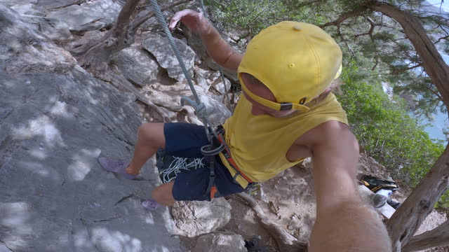 POV rock climber being belayed to the ground