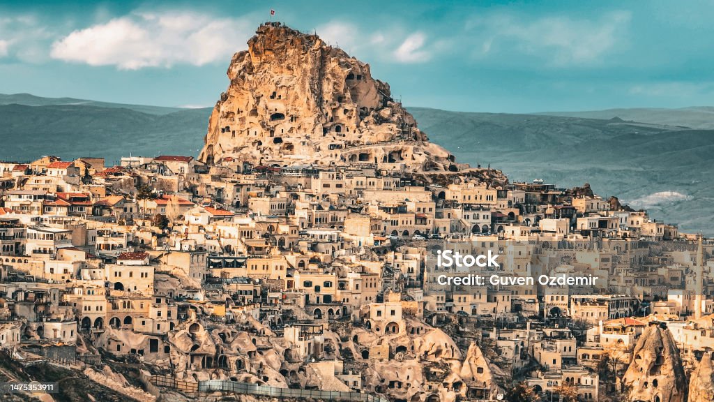 Aerial view of  Uchisar, Aerial view of cappadocia, Uçhisar castle, famous place of turkey, natural formation fairy chimneys, unesco heritage destination, Aerial view of Cappadocia, historical region in Central Anatolia, old settlement, village of stone Uçhisar is a village in Cappadocia, in Nevşehir province, Turkey. It is 7 kilometres east of Nevşehir, 12 kilometres west of Ürgüp, and 10 kilometres south of Avanos. Situated on the edge of Göreme National Park, Uçhisar consists of an old village huddled around the base of a huge rock cone and a new one closer to the road that runs from Nevşehir town to Göreme. Rock Hoodoo Stock Photo