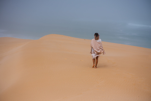 Rear view of woman walking along sand dune