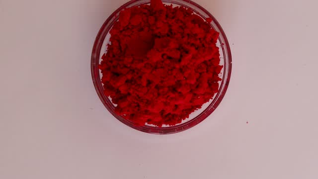 Red Holi Colors in Transparent Bowl Table Top View Spin