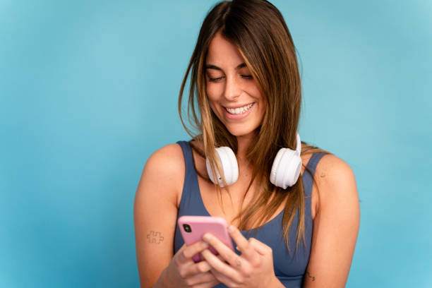 istock Smiling woman in headphones using smartphone 1475361265