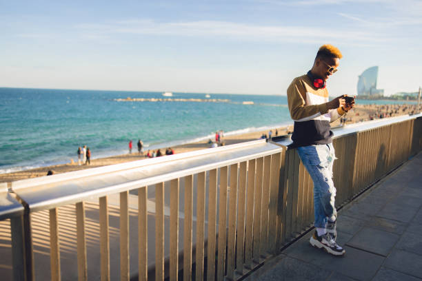 istock Young male adult using phone next to the public beach 1475361349