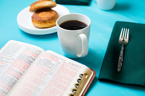 Friends share coffee and a snack as they study the Bible together.  Green napkins on a turquoise table cloth.