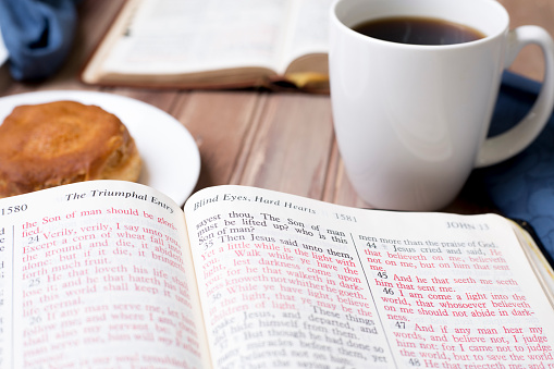 Friends share coffee and a snack as they study the Bible together.  Blue napkins on wood table top.