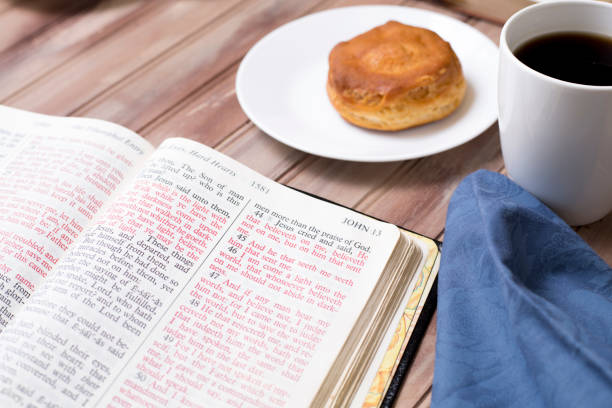 Friends share coffee and a snack as they study the Bible together.  Blue napkins on wood table top.