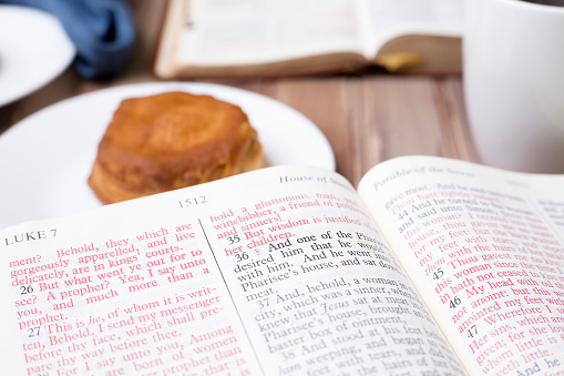 Friends share coffee and a snack as they study the Bible together.  Blue napkins on wood table top.