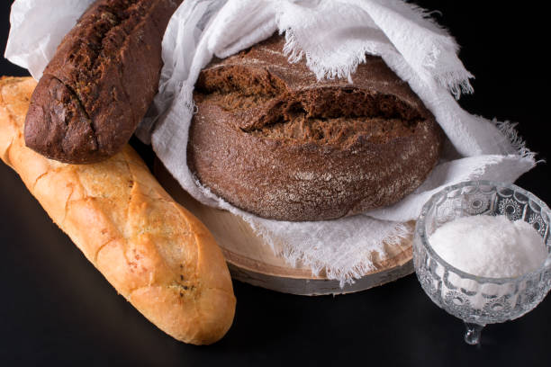 istock Fresh round black bread with a crispy crust. Close-up on a black background 1475362735